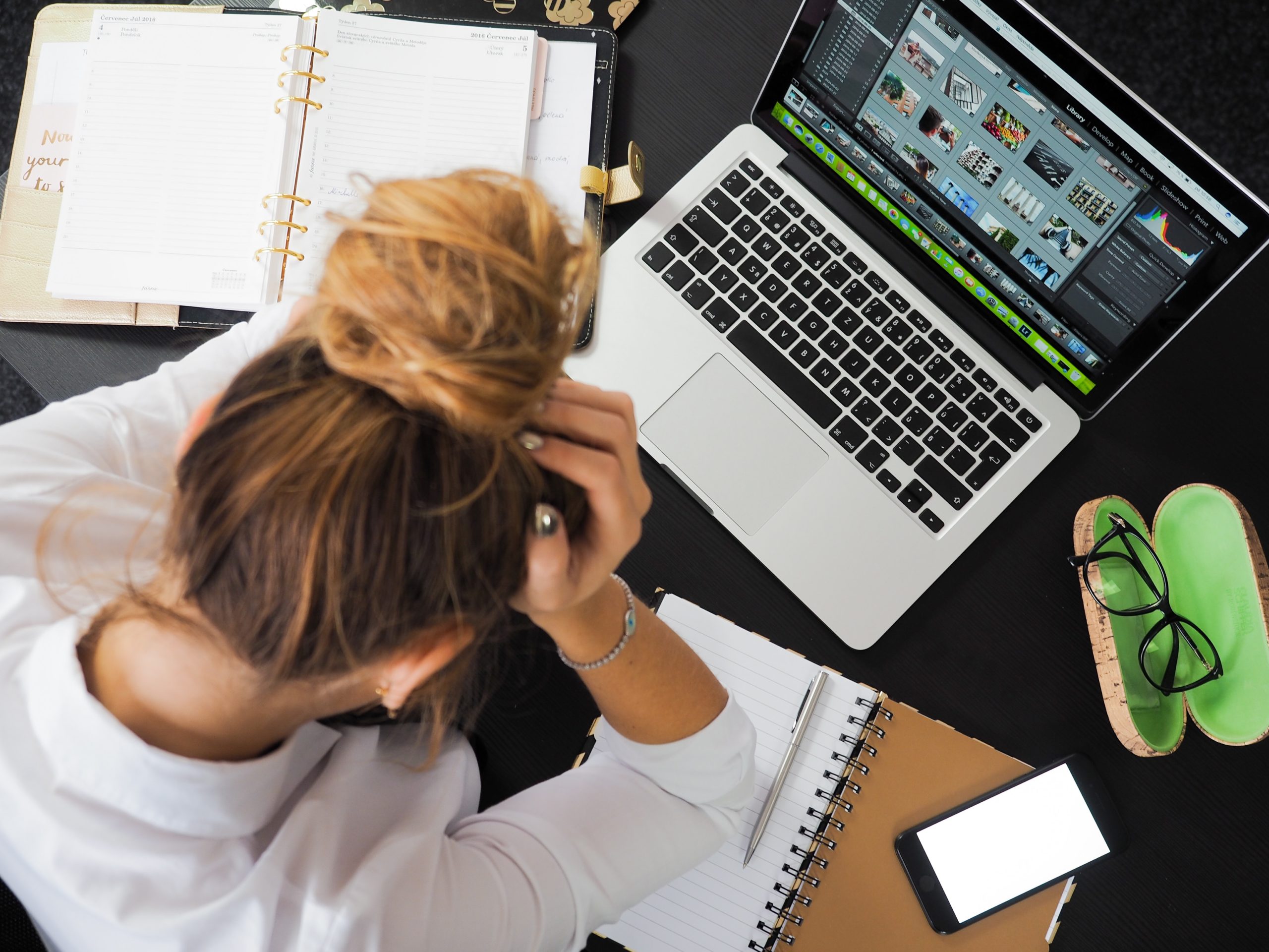 Entrepreneur stressé face aux défis de gestion des finances personnelles, entouré de carnets et ordinateur.