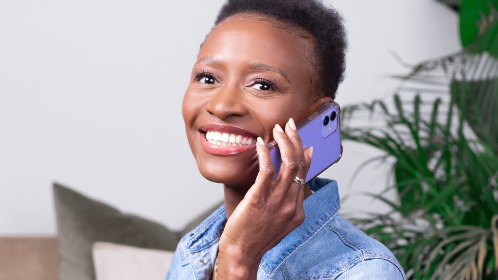 Photo de Solange Baboy souriante tenant un téléphone violet, symbolisant la convivialité et la disponibilité pour la page de contact De la finance.