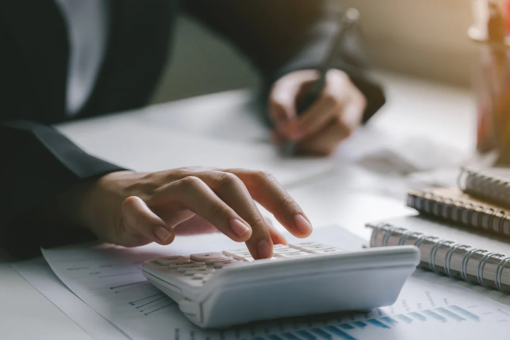 Expert comptable utilisant une calculatrice pour analyser les coûts et la rentabilité d'une entreprise.